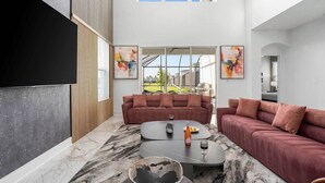 A modern living room with a large window, a sofa set, and a coffee table. - The Glorious | NEW designer home next to Universal ft. glam BRs, theme RMs, pool (Orlando)
