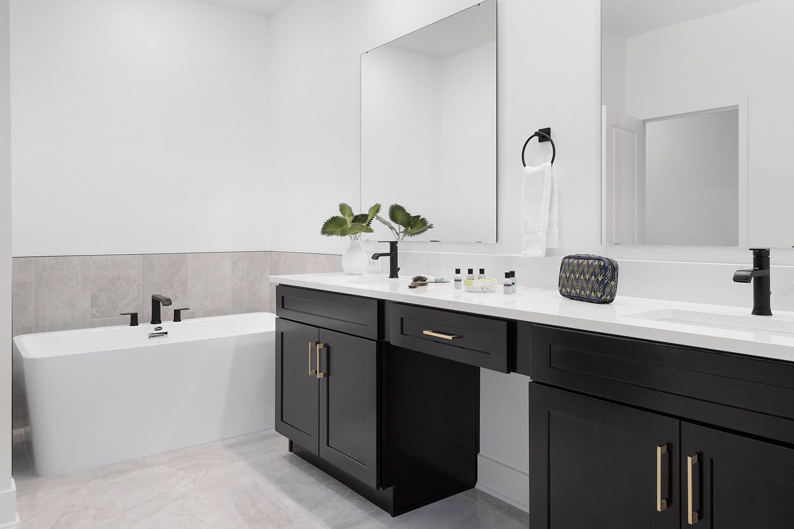 A modern bathroom with a white sink, black cabinets, and a large mirror.