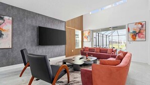 Uma sala de estar moderna com sofá modular, uma poltrona de couro preta e uma televisão de tela plana fixada em uma parede com textura.