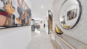 Um corredor moderno com piso de mármore, escada e obras de arte nas paredes.