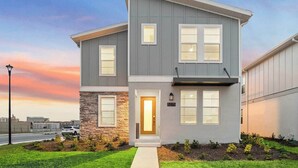 A modern two-story residential building with a stone accent wall, a well-maintained lawn, and a street lamp.