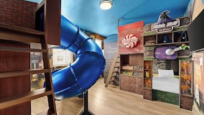A children's play area with a blue slide, a hat shop, and a candy store.