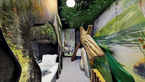 A narrow corridor with a bed, a mural, and a green wall.