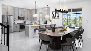 A modern kitchen with grey cabinets, stainless steel appliances, and a central island with seating. - Magnificent Mansion | Breathtaking estate mins to Universal, Disney, restaurants (Orlando)