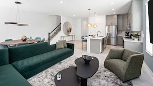 Un salon moderne avec un canapé vert, deux tables basses noires et un tapis gris.