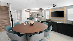 Un espace repas moderne avec une table ronde, des chaises de couleur turquoise et un luminaire central.