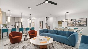 Un salon moderne avec un canapé bleu, deux fauteuils orange et un sol à motifs de marbre.