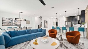 Un salon moderne avec un canapé bleu, des fauteuils orange et un sol en marbre.