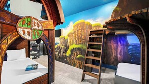 Una habitación con una cama, una escalera y un mural de un paisaje forestal.