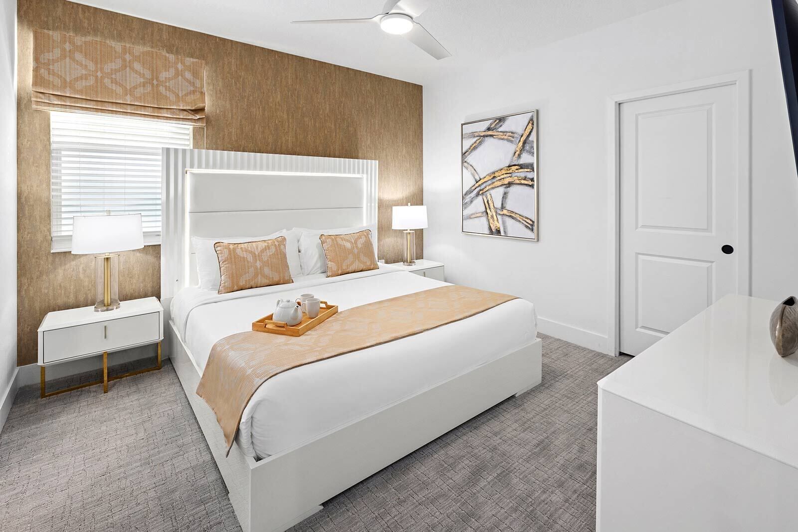 Una moderna camera d'albergo con un letto grande, comodini, una ventola a soffitto e un quadro appeso al muro.