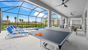 A pool table with lounge chairs and a view of a swimming pool and palm trees. - Majestic Marvel | Showstopping estate on I-Drive w/ 2 theme RMs, theater, arcade (Orlando)