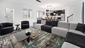 Ein modernes Wohnzimmer mit einem Ecksofa, einem Couchtisch und einem Deckenventilator.
