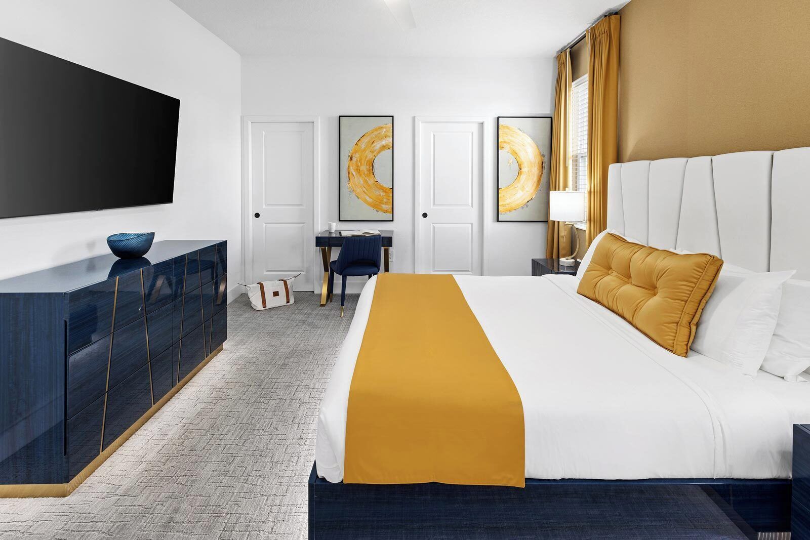 Une chambre d’hôtel moderne dotée d’un grand lit, d’un bureau, d’une télévision à écran plat et d’œuvres d’art accrochées aux murs.