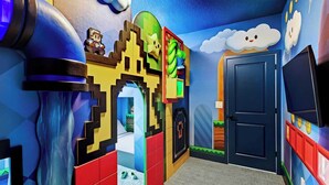 Una habitació amb un disseny de castell pixelat, una porta i un televisor a la paret.
