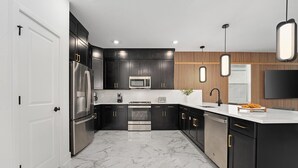 Una cocina moderna con armarios oscuros, un refrigerador de acero inoxidable, un microondas y una estufa.