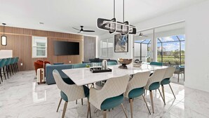 Un comedor moderno con suelo de mármol, una gran mesa blanca y sillas color turquesa.