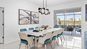 Un comedor moderno con una mesa grande, sillas color turquesa y vistas a la ciudad a través de amplios ventanales.