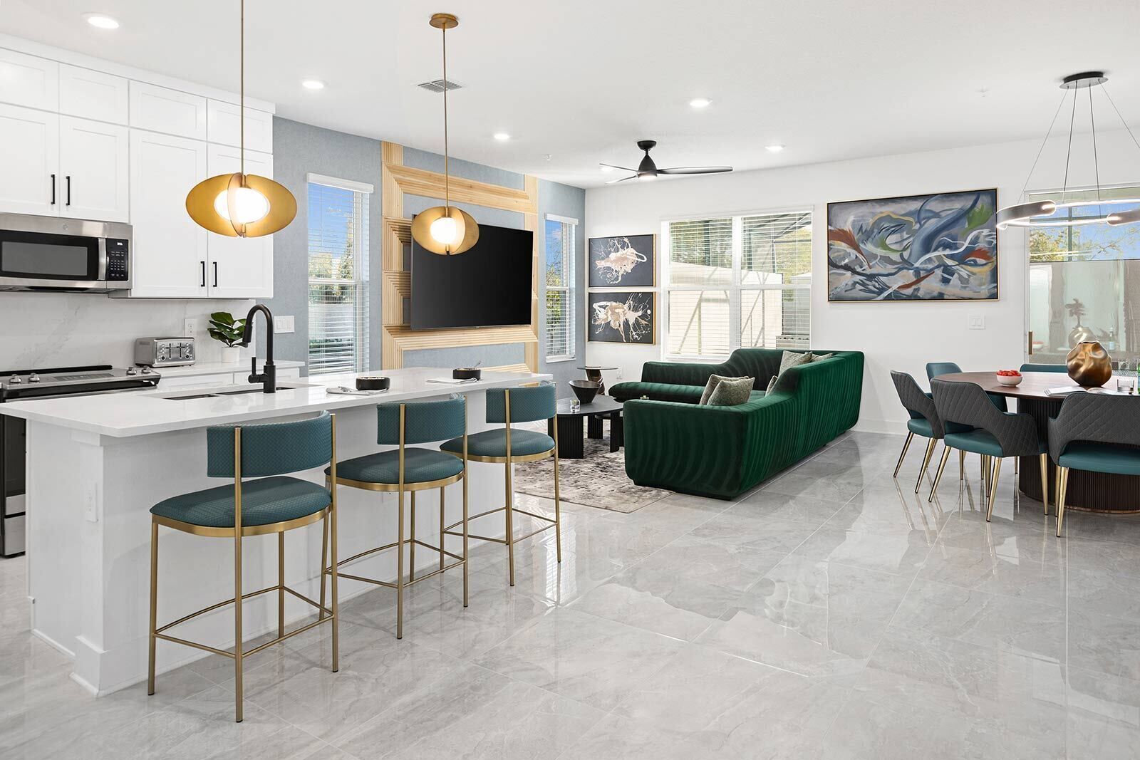 A modern kitchen with a central island, bar stools, a green sofa, and a dining area with chairs and a table.