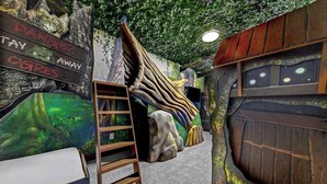 A room with a wooden ladder, a sign warning 'Danger, Stay Away, Ogres', and a mural of a forest scene.