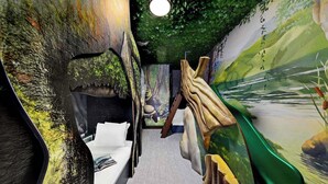 A narrow corridor with a bed, a mural, and a green wall.