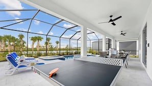 A spacious outdoor area with a ping pong table, lounge chairs, and a pool. - Wondrous Wonderland | A dream escape on I-Drive - theme RMs, PVT pool, theater (Orlando)