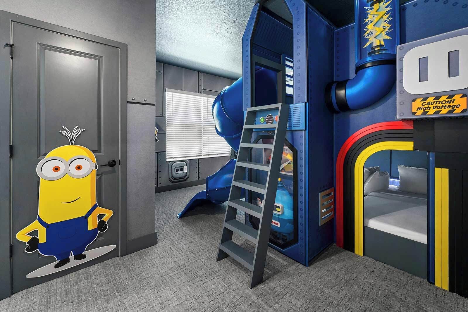 Zona de juegos con un tobogán, una decoración de Minions y un letrero de precaución.