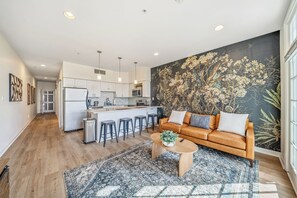 Une cuisine moderne avec des meubles blancs, un îlot central doté de tabourets et un grand mur décoratif.