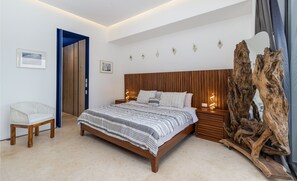 Une chambre à coucher moderne avec un lit en bois, des tables de chevet, une chaise et une sculpture en bois originale.