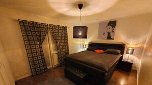 Ein Schlafzimmer mit einem Bett, einem Sessel, einer Hängelampe und einer Wandleuchte.