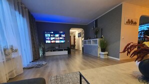 Ein modernes Wohnzimmer mit einem Flachbildfernseher an der Wand, einem Sofa und einem Couchtisch.