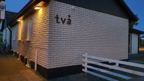 Ein Gebäude aus Backsteinen mit einem weißen Zaun davor, mit der Aufschrift "tva".