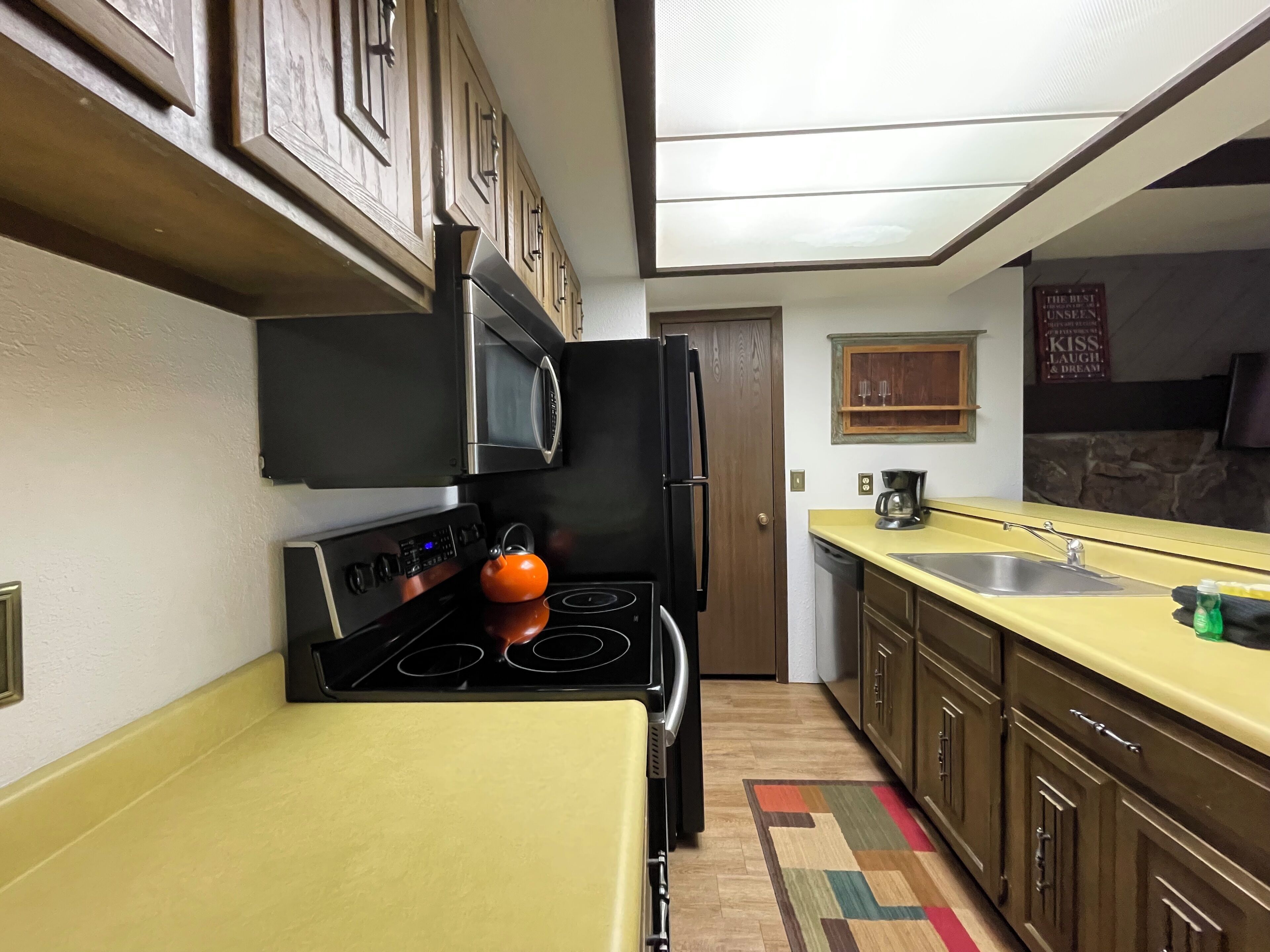 Una cocina con encimera amarilla, electrodomésticos negros y armarios de madera.