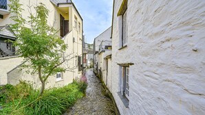 Un estrecho callejón entre edificios, con un pequeño arroyo corriendo por él.