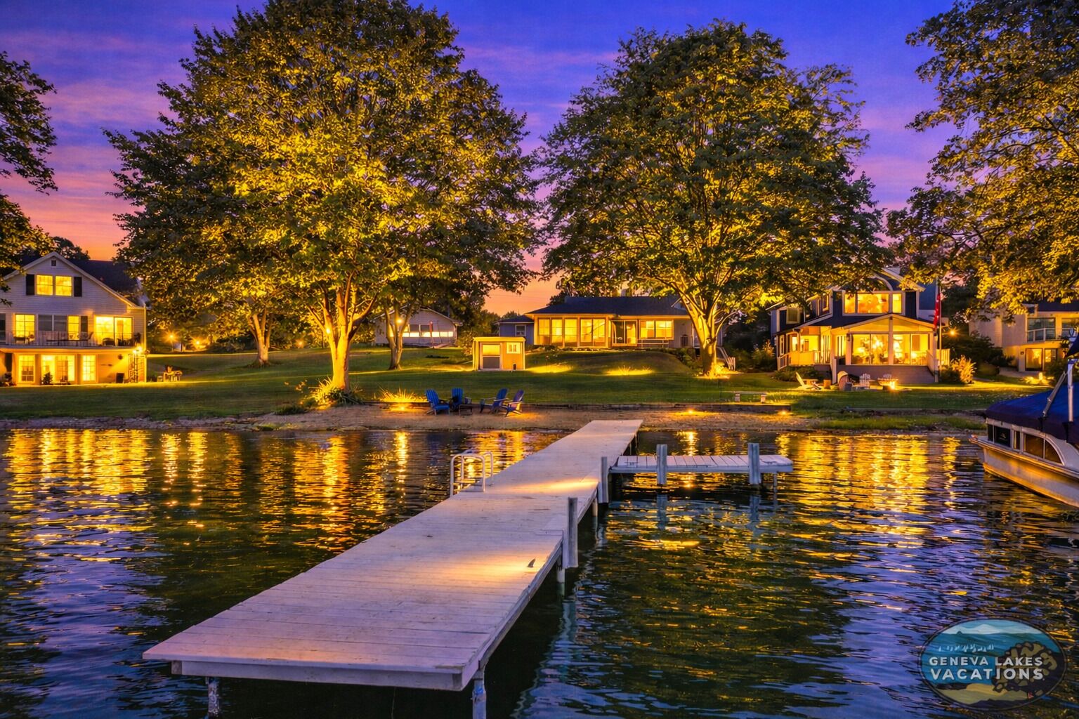 A lakeside property with a dock, houses, and trees.