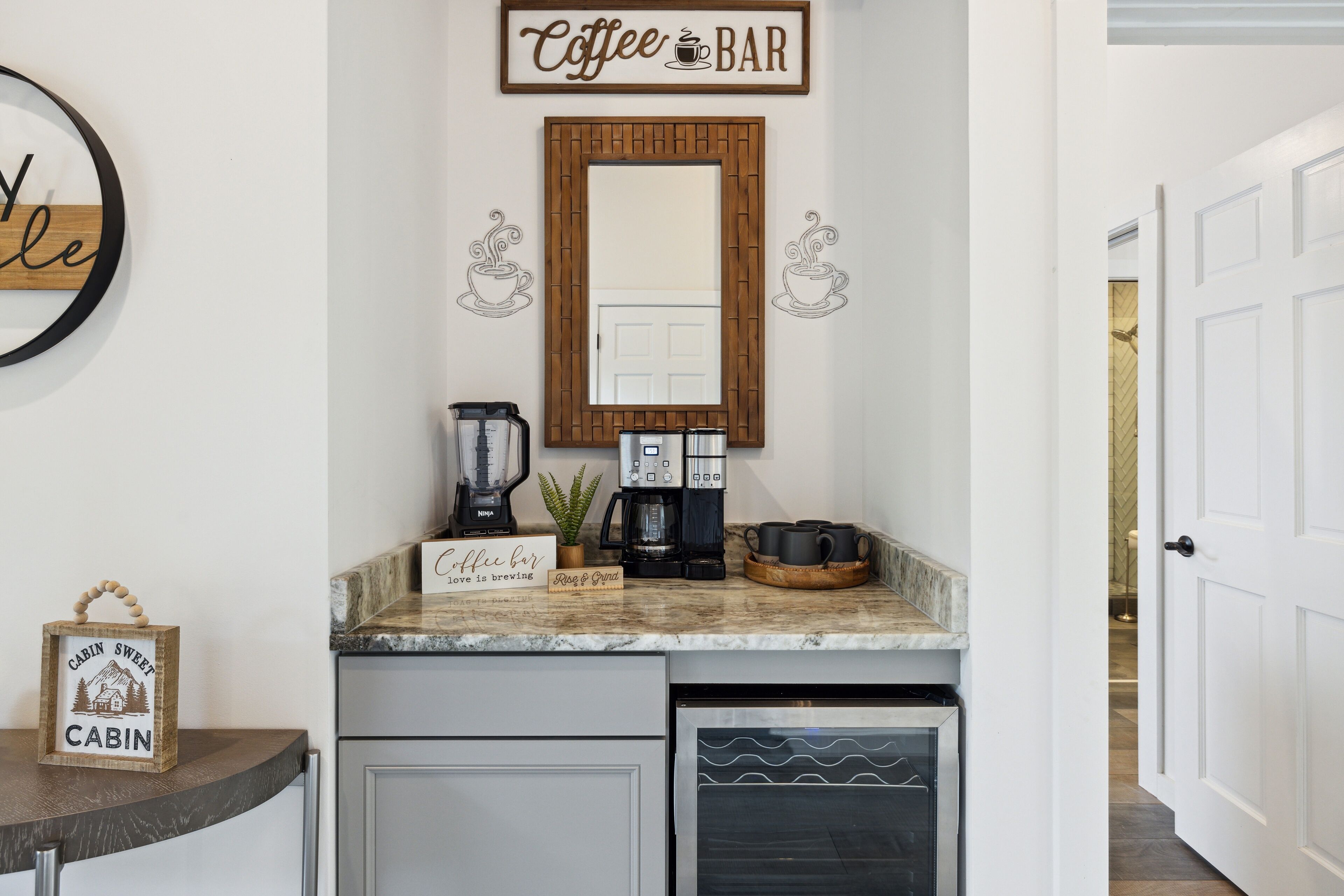 A kitchen area with a coffee bar setup, including a coffee maker, grinder, and a sign that says "Coffee Bar."