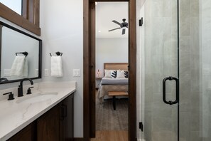 A modern bathroom with a large mirror, a sink, and a shower area. - Hay Meadow Lodge 3 Bedroom Townhouse by RedAwning (Fraser)