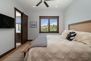 A bedroom with a bed, a window with a view, a ceiling fan, and a TV mounted on the wall. - Hay Meadow Lodge 3 Bedroom Townhouse by RedAwning (Fraser)