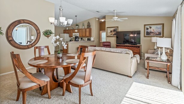 A spacious living room with a dining area, a sofa, a TV, and a ceiling fan.