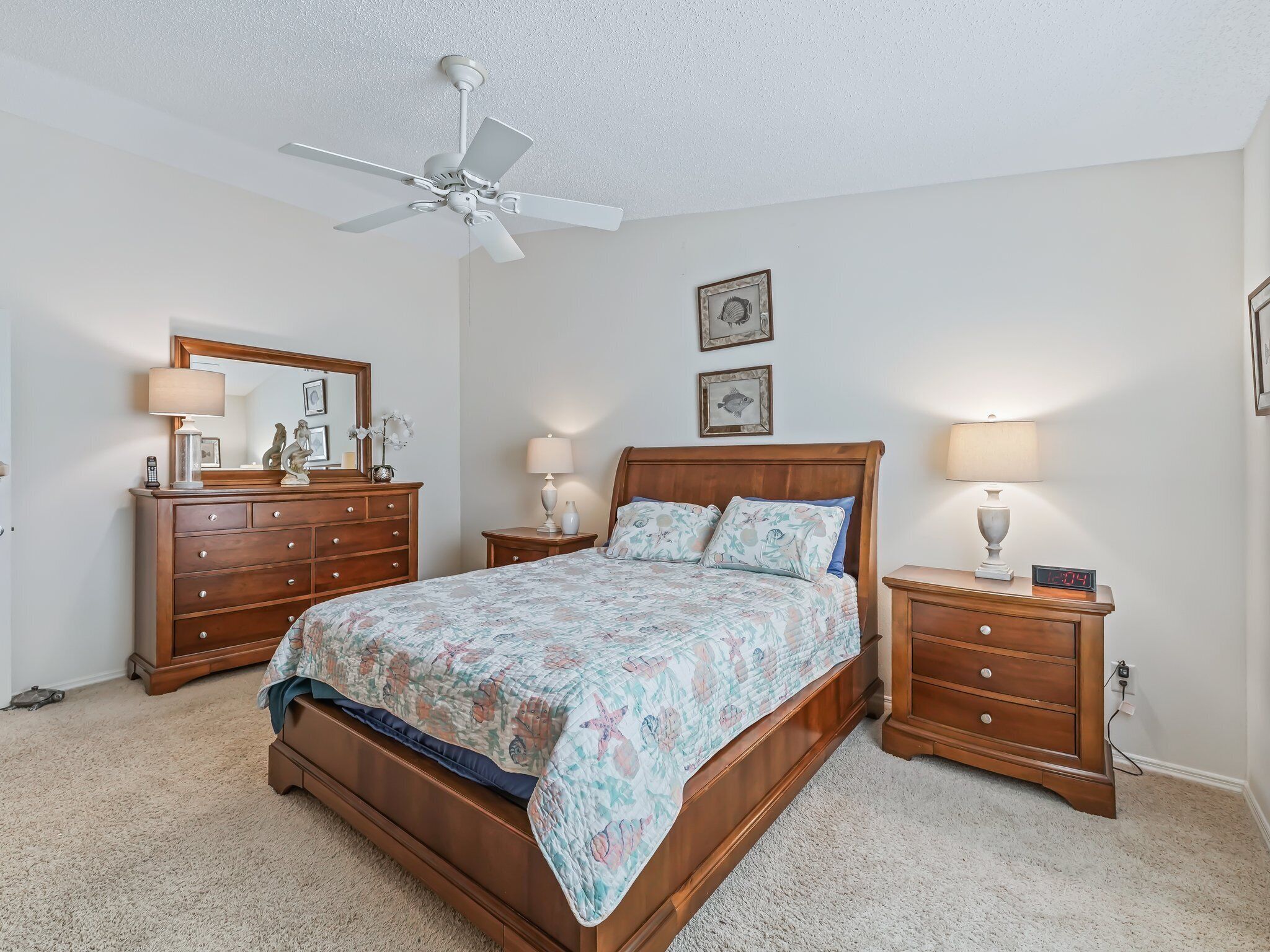 A bedroom with a wooden bed, two nightstands, a ceiling fan, and a dresser.