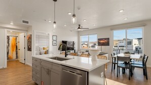 A modern kitchen with a large island, stainless steel appliances, and pendant lighting. - Coco Dunes 2 Bedroom Condo (St. George)