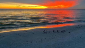 A beach with a sunset over the ocean. - Beyond The Sea · 70+ 5-Star ·  Walk to Beach-Town (Fort Myers Beach)