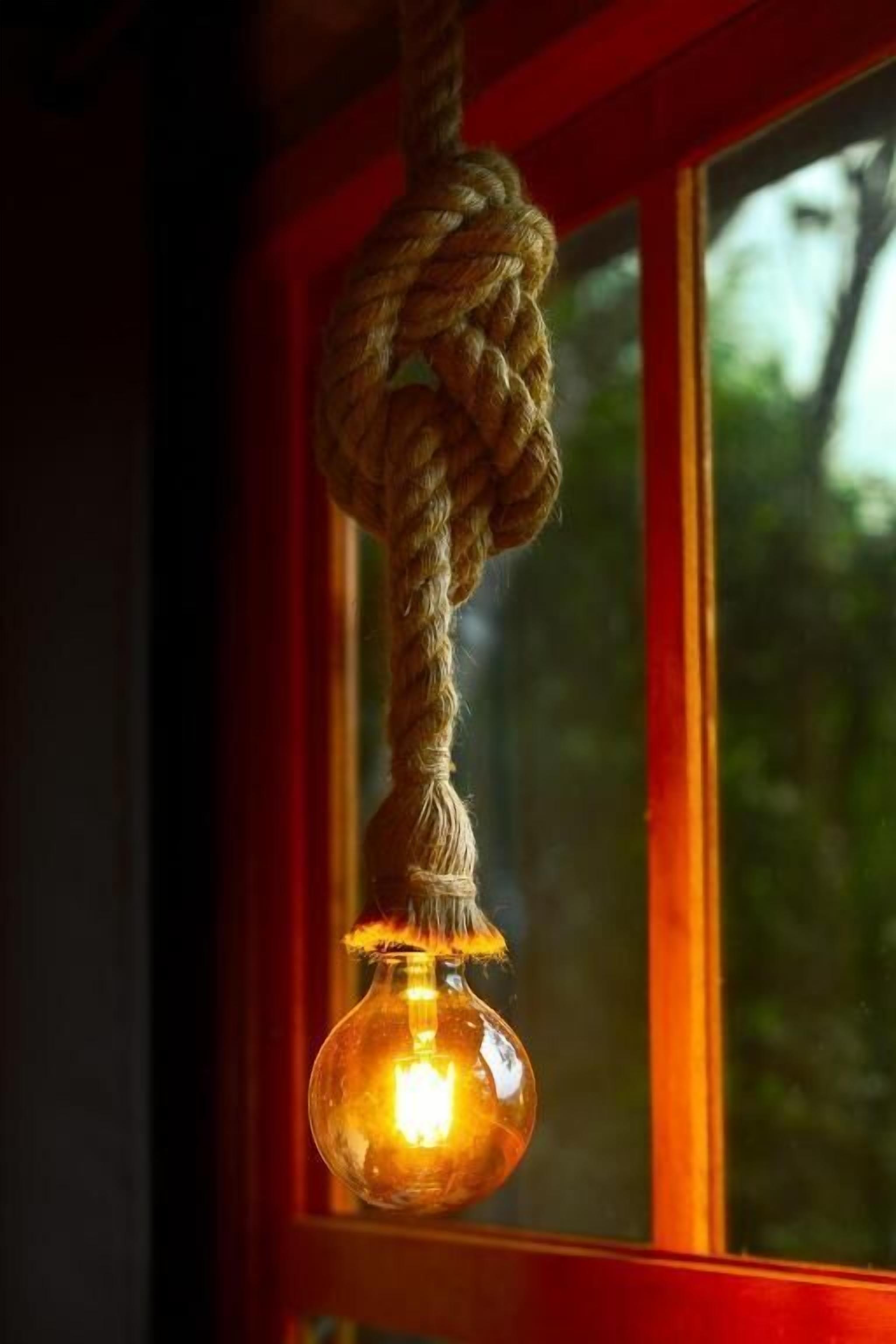 A rope light fixture hanging from a window with a red frame.