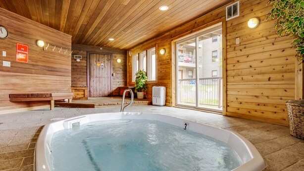 A wooden cabin interior with a hot tub, wooden walls, and a bench.