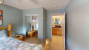 A bedroom with a bed, bedside table, and a mirror.