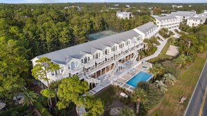 A large, multi-story hotel with a swimming pool, surrounded by dense forest.
