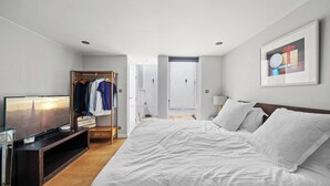 Une chambre d’hôtel comprenant un lit, une télévision, une armoire et une porte donnant sur une autre pièce.