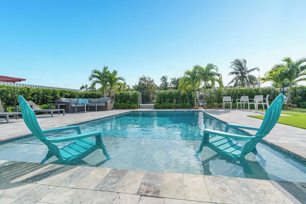 A rectangular swimming pool with two turquoise lounge chairs facing each other.