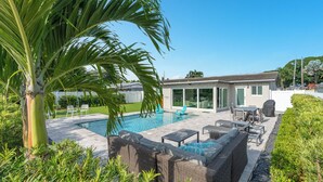Une maison moderne dotée d’une piscine, de mobilier d’extérieur et d’un jardin bien entretenu.