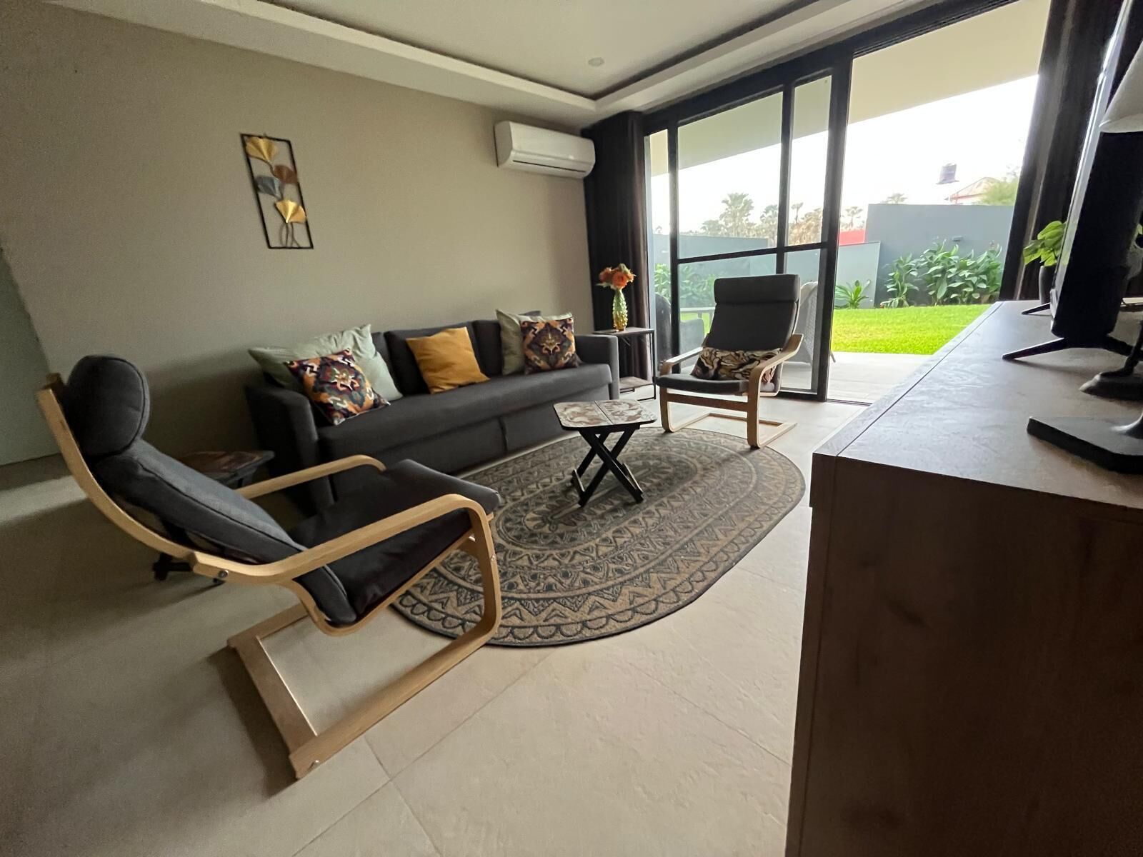 A modern living room with a sofa, two chairs, a coffee table, and a desk.