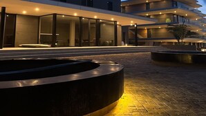 Un bâtiment moderne doté d’une cour intérieure, comprenant une fontaine circulaire et un espace aménagé pour s’asseoir.